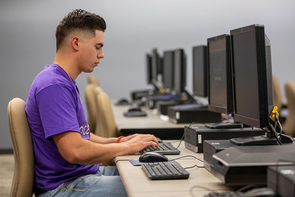 一名火博体育的学生在校园电脑室里使用电脑